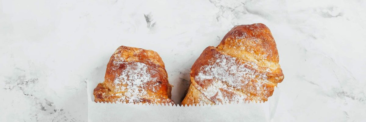 two-fresh-croissants-in-a-paper-bag-on-a-marble-ba-2021-09-02-20-18-47-utc-min-scaled